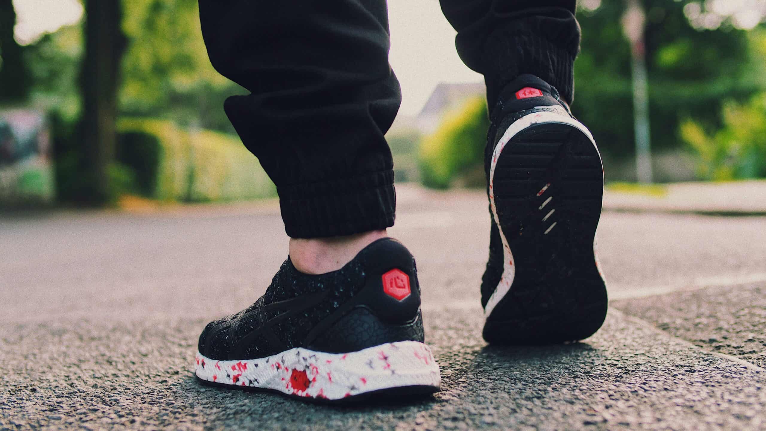 Close-up of a person walking with stylish sneakers on a bright street.