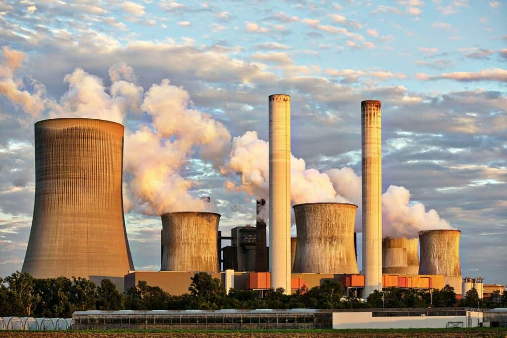 View of a power plant with smoke emissions under a cloudy sky, depicting industrial energy production.